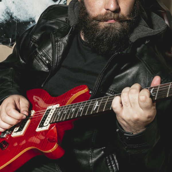 Guitarrista tocando acordes en una guitarra roja