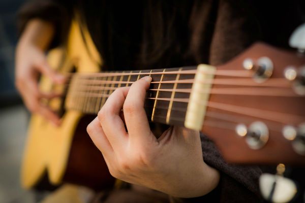 Mulher toca violão de seis cordas de aço