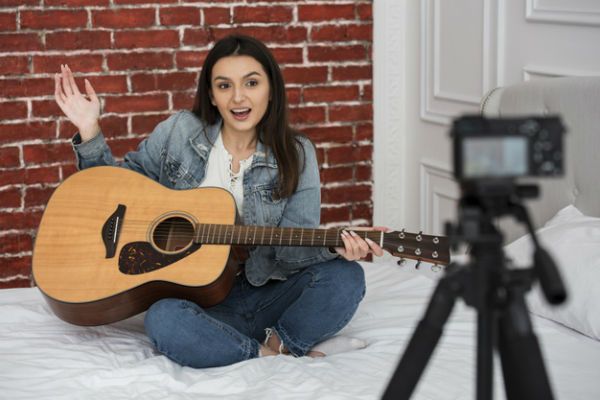Jovem mulher gravando vídeo de como tocar violão