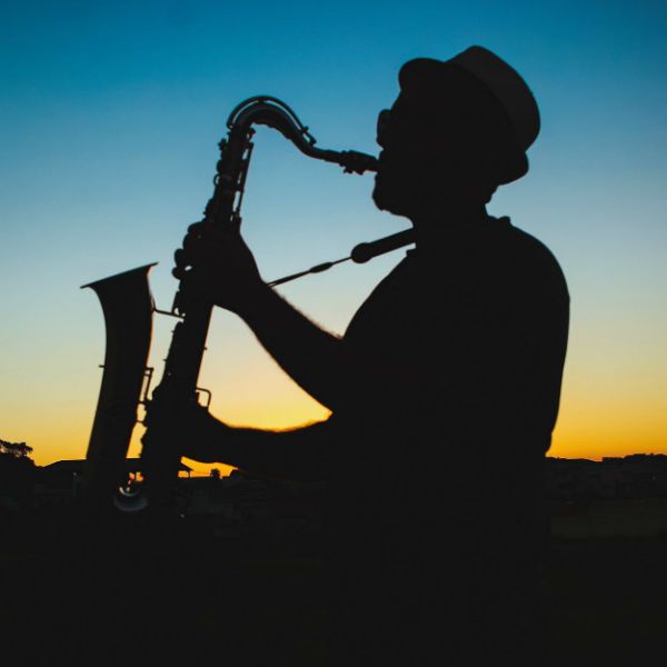 Silhueta de homem tocando saxofone com um belo pôr do sol ao fundo