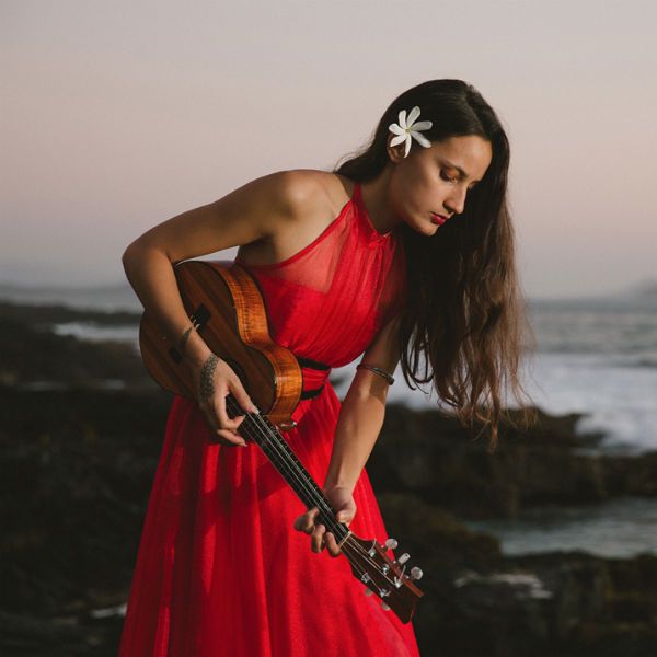 taimane gardner toca ukulele, de costas pro mar, de vestido vermelho