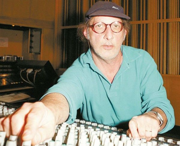 De boné e óculos, o produtor musical Arnaldo Sacomanni trabalha em uma mesa de som