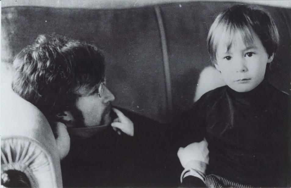 John Lennon e o filho Julian deitados em um sofá.