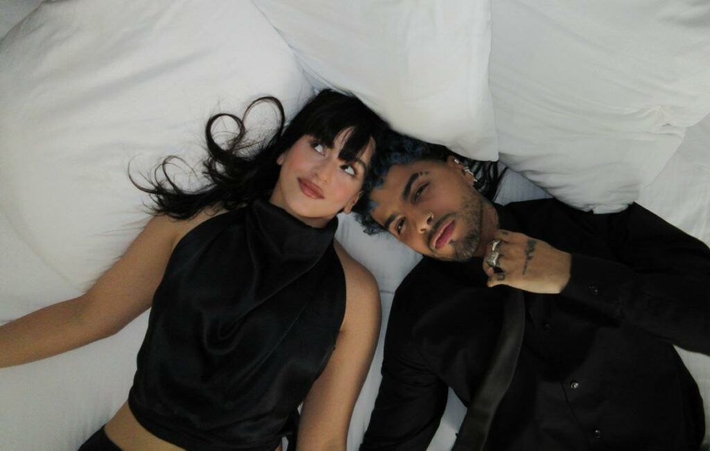 En la imagen, se ve a Rosalía y Rauw Alejandro acostados en una cama