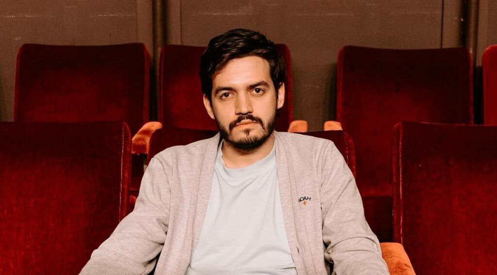 Juan Pablo Villamil mirando hacia la cámara, sentado en una butaca roja