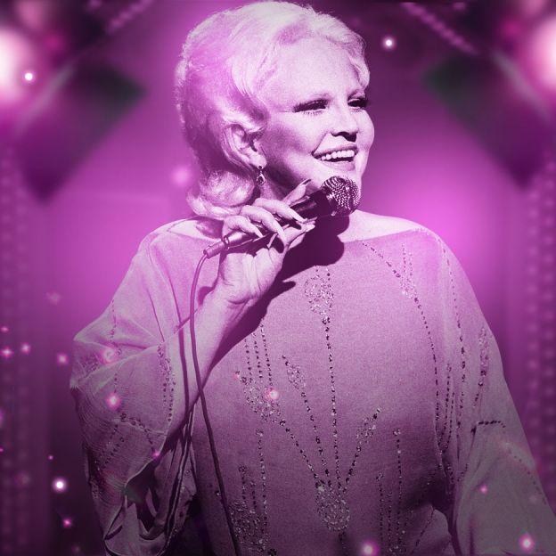 A cantora Peggy Lee canta ao vivo no centro da imagem