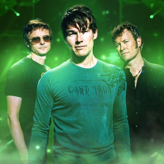Integrantes da banda A-ha posam lado a lado no centro da imagem