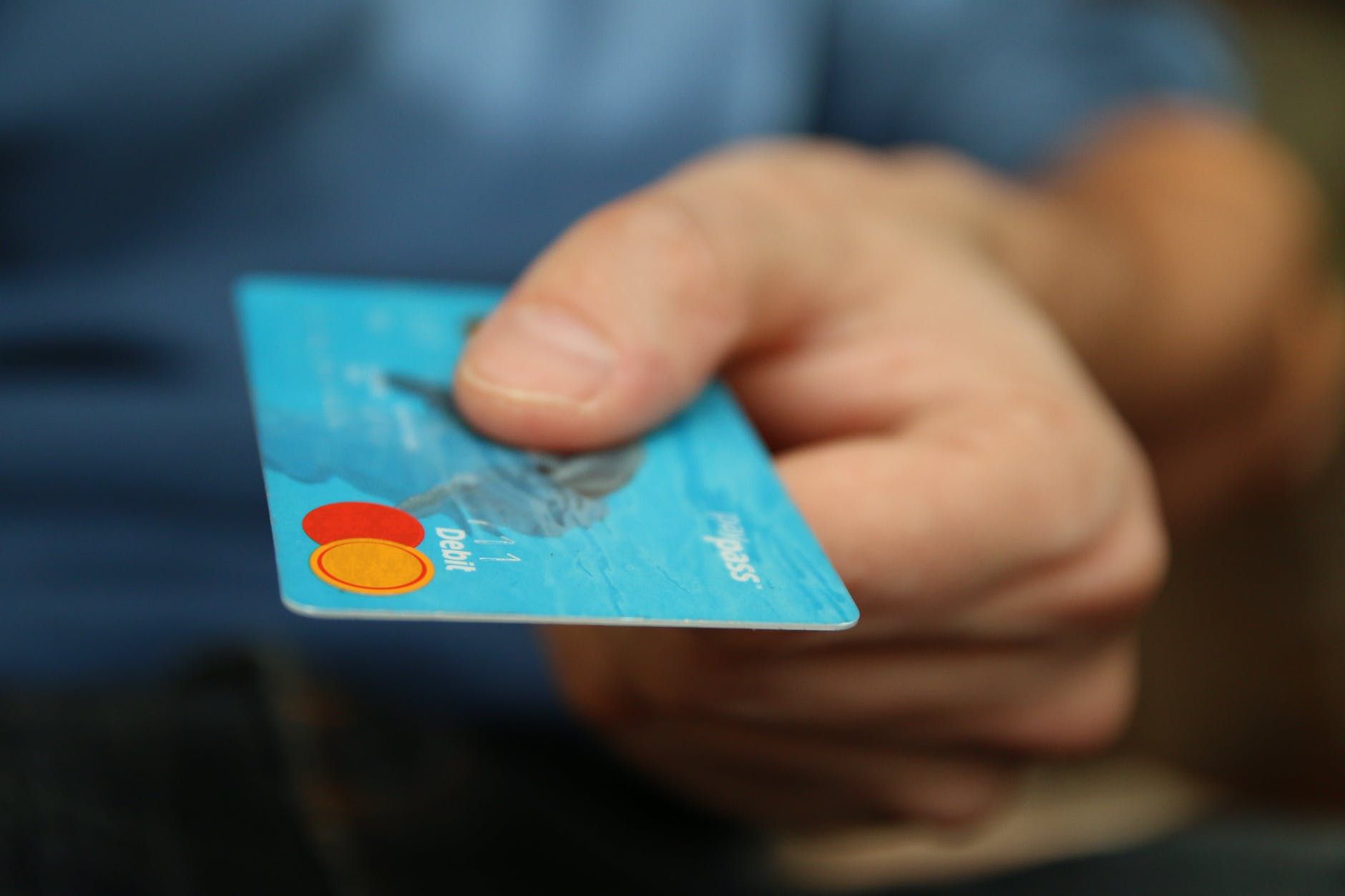 Mão de um homem oferece Cartão de débito como forma de pagamento