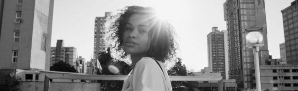 Foto em branco e preto mostra a cantora Malaca contra a luz do sol