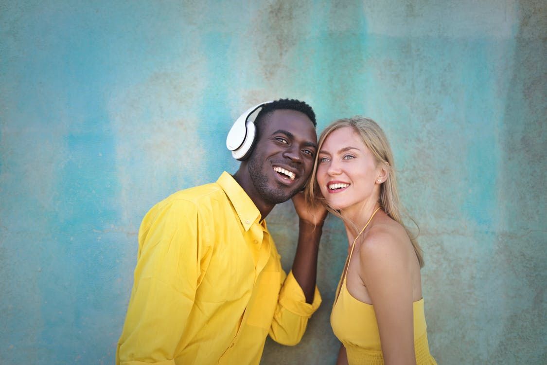 Homem negro e mulher loira ouvindo música, juntos