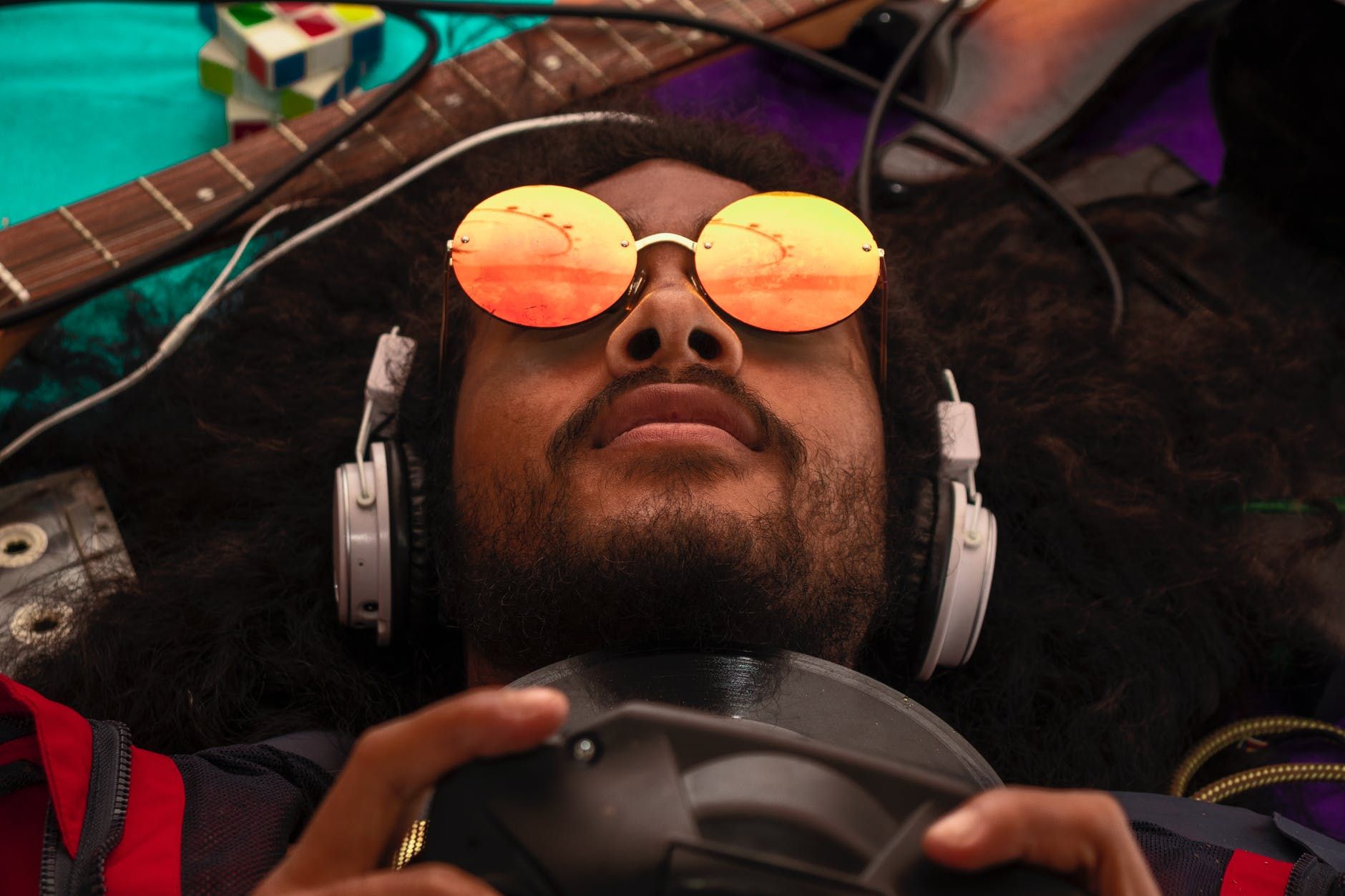 Homem negro jogando videogame e rodeado por instrumentos musicais