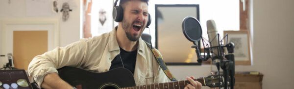 Músico grava voz e violão em estúdio