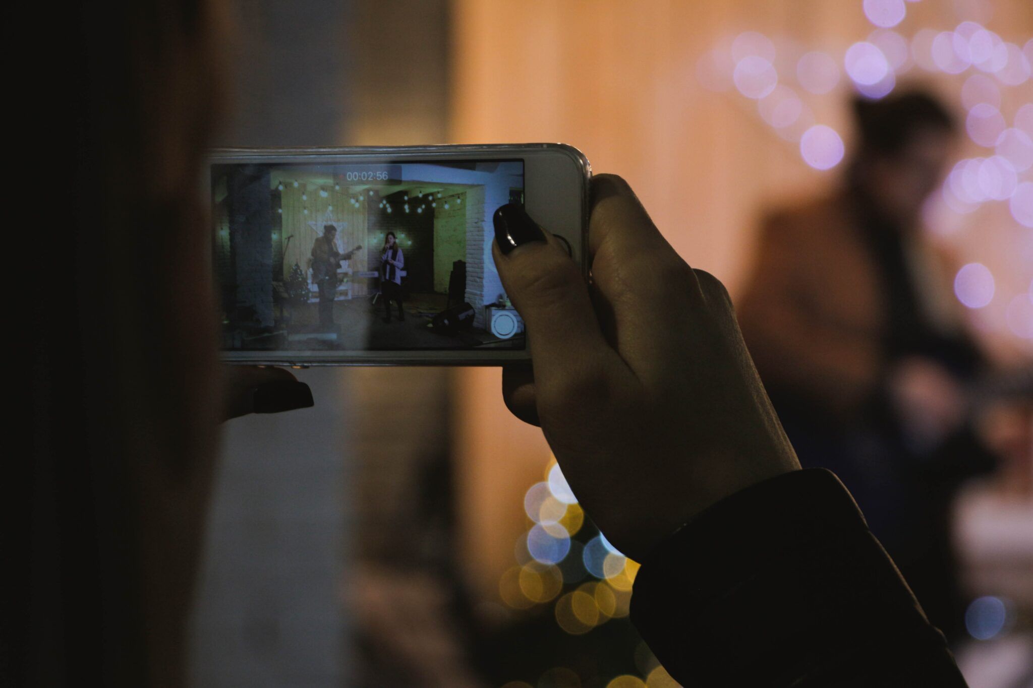 Pessoa filmando uma apresentação musical pelo smartphone