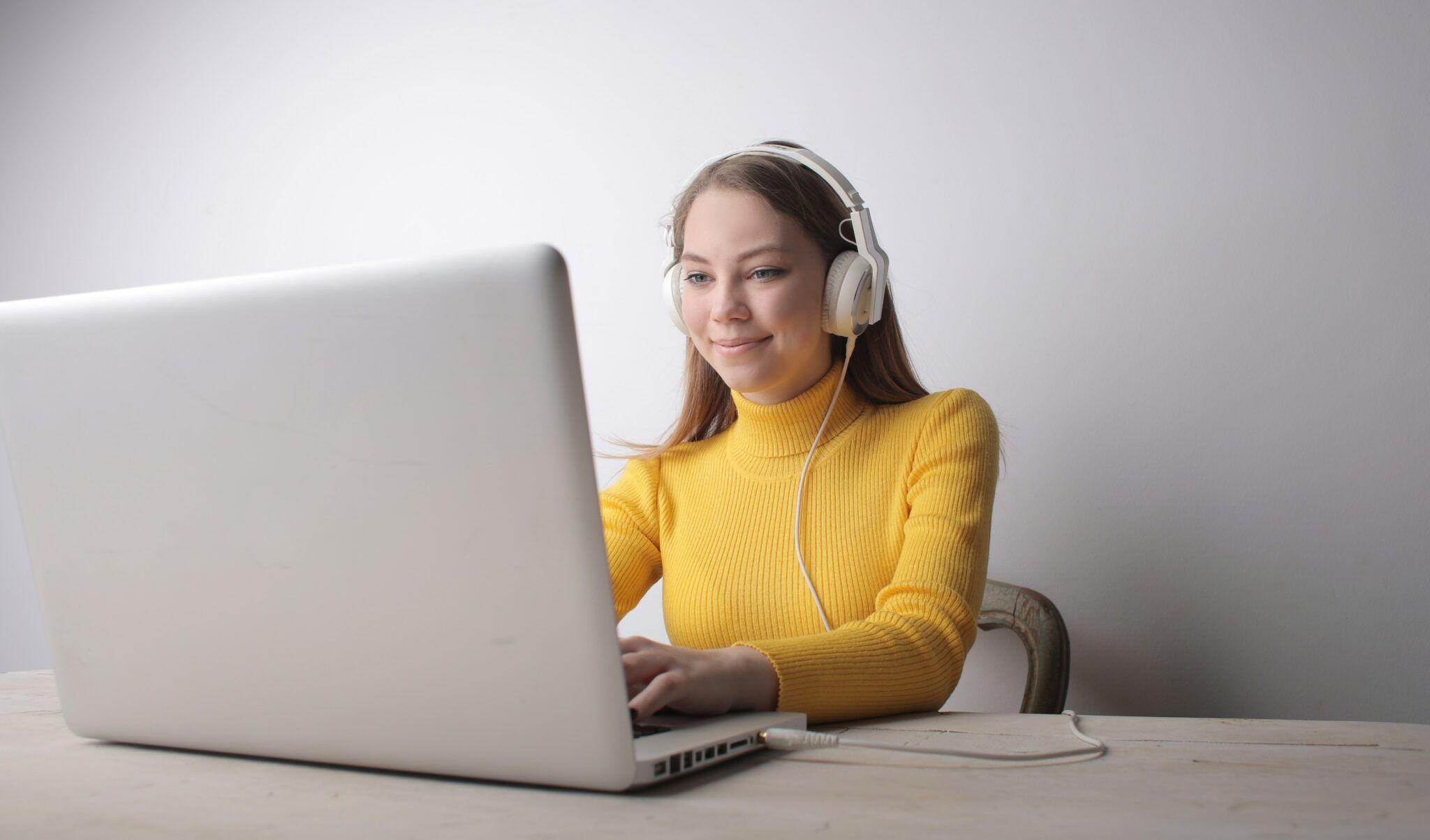 Mulher de amarelo com fones de ouvido acessando um blog de música no computador