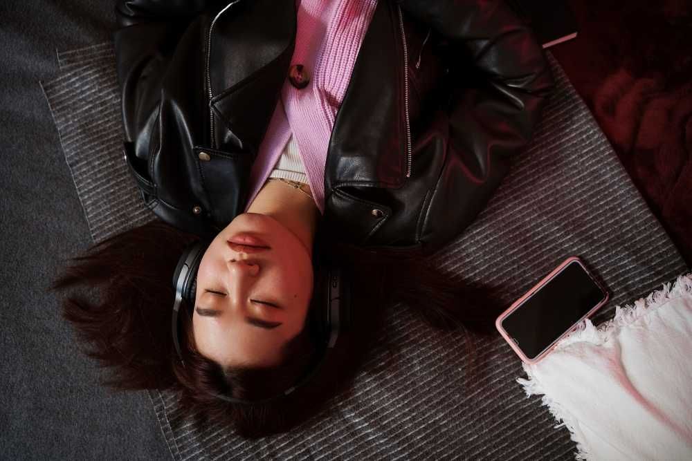 Mulher deitada no chão ouvindo música com um headphone