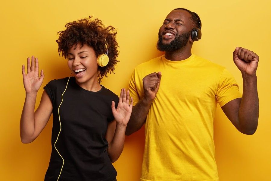 Casal de jovens felizes e dançando, enquanto ouvem música em fones de ouvido